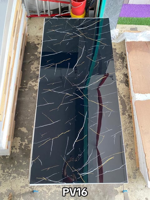 Black marble tile sample labeled PV16 with white and red veining patterns on concrete floor among other tiles