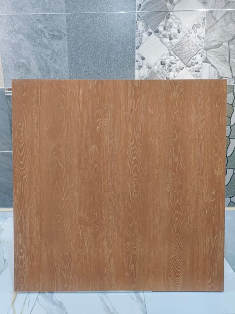 Wood grain flooring sample displayed on marble surface with tile samples in background