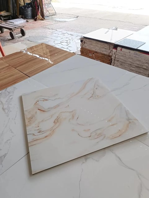Marble tile samples displayed on white surface in construction or design showroom with wooden flooring and blueprint samples visible