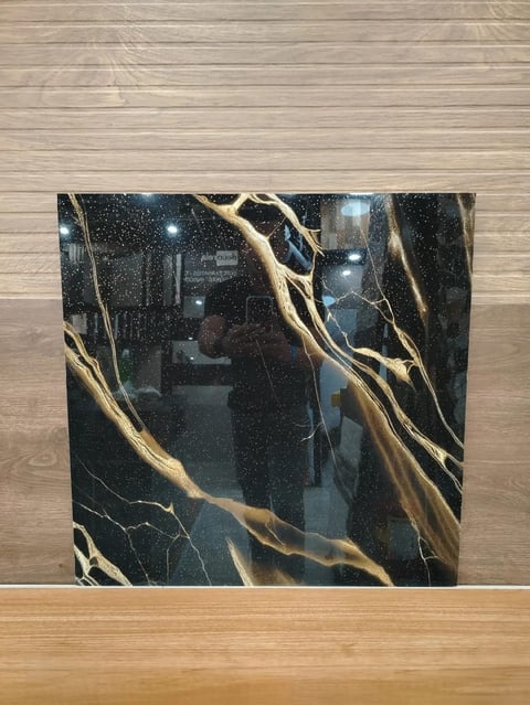 Black marble tile with gold veining displayed on light wood flooring
