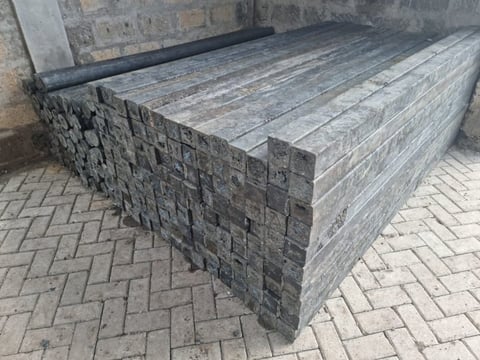 Two stacks of weathered wooden railroad ties or timber beams arranged parallel with a gap between them