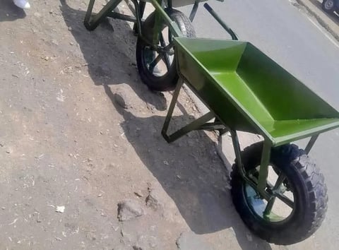 Green hand truck or dolly with black metal frame and large wheels on pavement