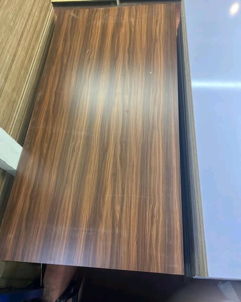 Close-up of wood grain texture on laminate or veneer material with vertical striations and warm brown tones