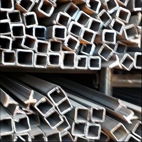 Stack of metal square tubes and hollow sections in various sizes arranged at an industrial storage facility