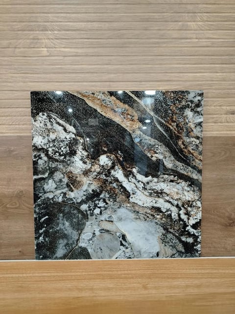 Abstract black and white marble tile with gold veining leaning against wooden wall