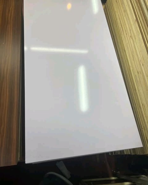 A blank white computer monitor screen framed by wooden and textured borders, with reflected light visible on the display