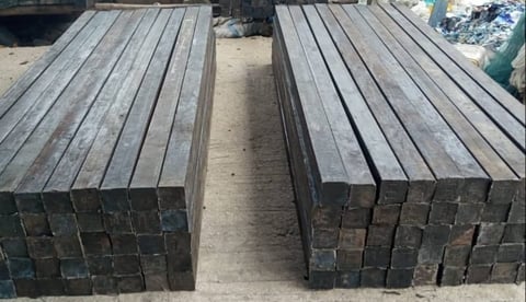 Two stacks of weathered wooden railroad ties or timber beams arranged parallel with a gap between them