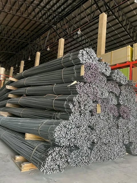 Industrial warehouse storing bundled steel pipes and rebar coils stacked on wooden pallets