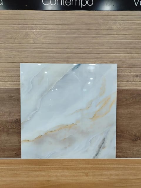 White and beige marble tile sample displayed on a wooden floor in a showroom