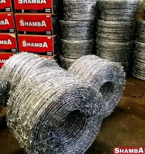 Rolled wire fencing displayed in a warehouse with red Shamba boxes stacked in the background