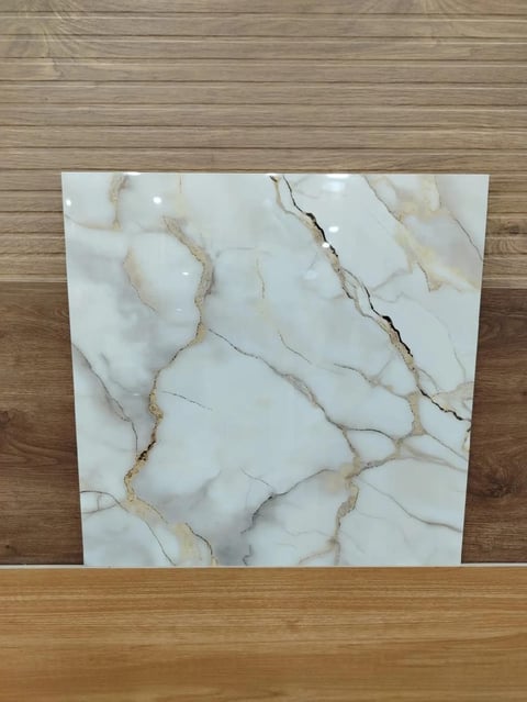 White marble tile with gold and gray veining leaning against wooden floor