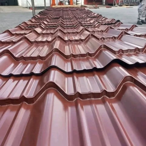 Stack of curved brown corrugated metal roofing tiles displayed at an industrial warehouse or construction site