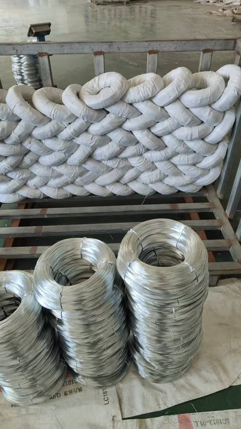 Industrial coils of wire and white rope stored on wooden pallets in a warehouse