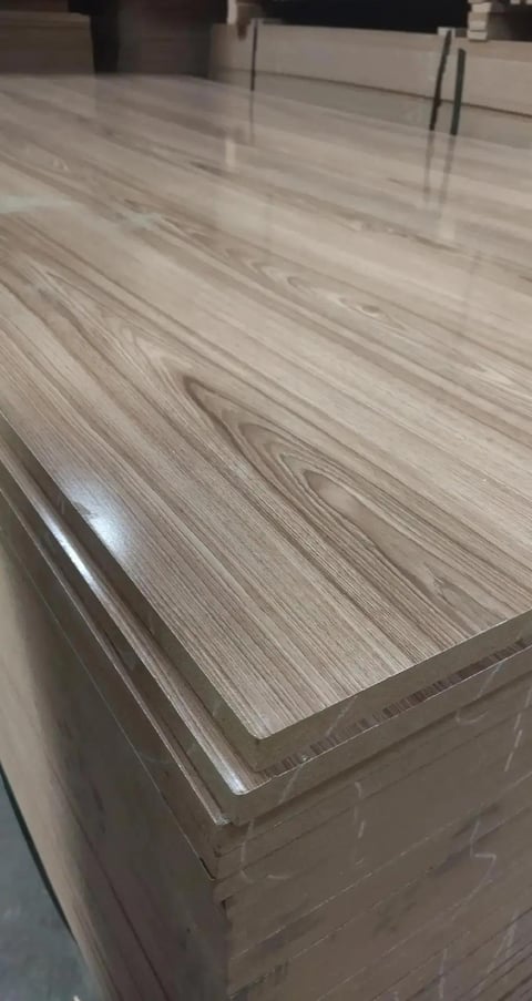 Stack of light gray wood-grain laminate flooring planks wrapped in plastic at an indoor showroom