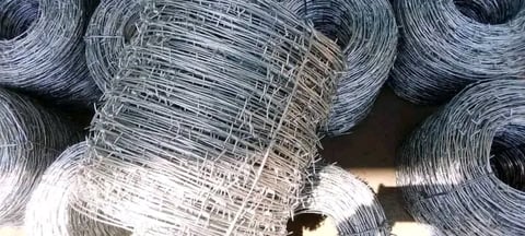 Rolls of galvanized wire mesh and metal fencing coiled and stacked in storage