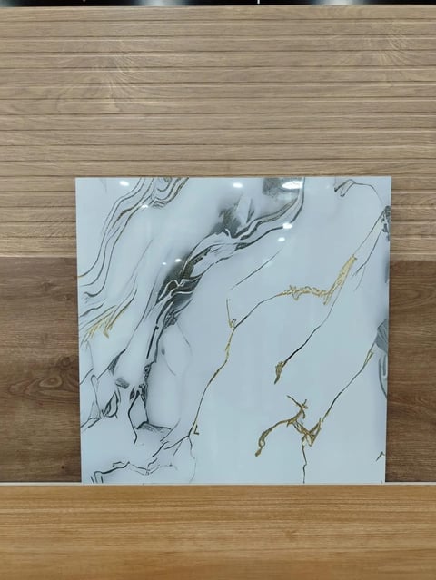 Abstract marble artwork with black and gray swirls and gold accents on white canvas, displayed on wooden table