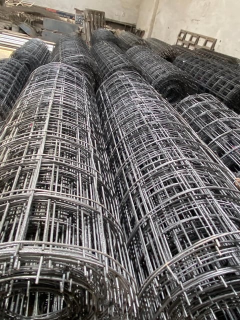 Rolls of welded wire mesh stacked indoors, showing metallic grid pattern used for construction reinforcement