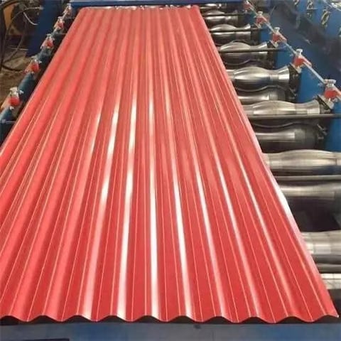 Red corrugated metal roofing sheet displayed with industrial machinery in background
