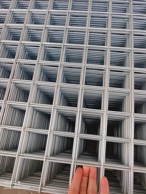 Hand pointing at metal wire mesh grid or fence with geometric pattern