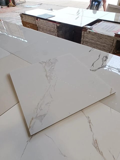 White marble-effect countertop samples displayed on showroom floor with wooden storage boxes in background