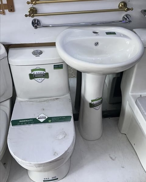 White ceramic bathroom fixtures including a low-flow toilet and pedestal sink with towel bars mounted on wall