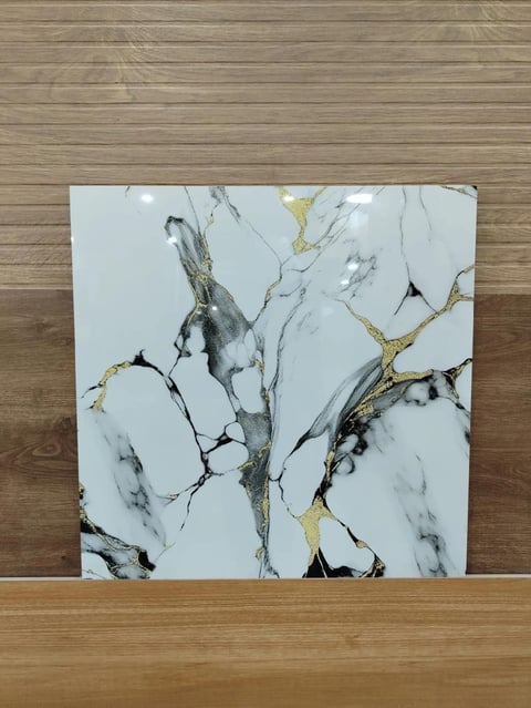 White marble tile with black and gold veining leaning against wooden floor