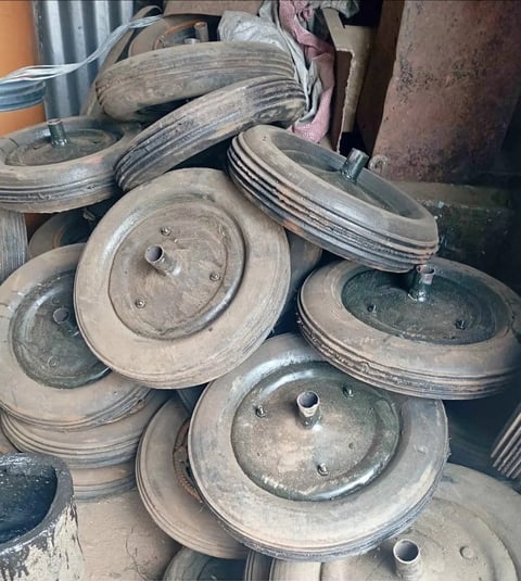Pile of old rusty car brake drums and rotors stacked in a storage area