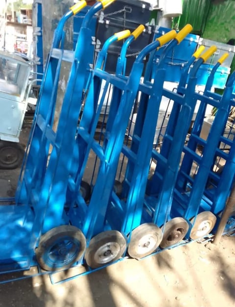 Blue industrial cable reels with yellow handles and metal spools arranged in a row at a manufacturing facility