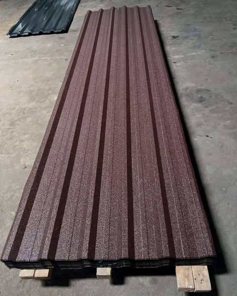 Burgundy corrugated metal roofing sheets stacked on pallets with black sheets visible in background