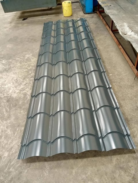 Corrugated metal roofing sheet with curved ridges laid on concrete floor in workshop or warehouse