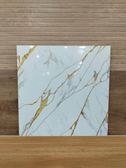 White marble tile with gold and gray veining displayed on wooden floor