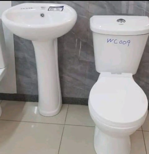 White pedestal sink and toilet on display in a bathroom showroom