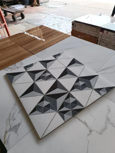 Geometric tile pattern with black and white triangles arranged in a 3D pyramid design on marble surface in workshop setting