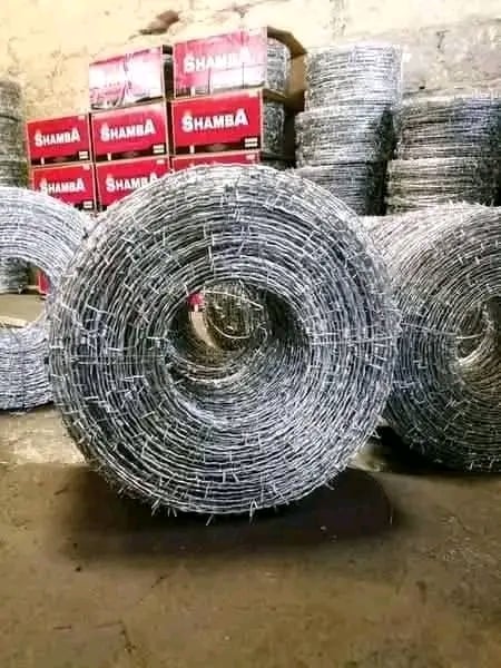 Rolls of welded wire mesh stacked in a warehouse with branded Shamba boxes