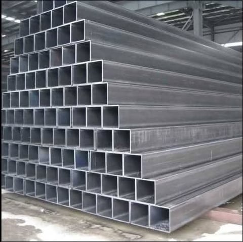 Stack of rectangular steel tubing in warehouse with fluorescent lighting overhead