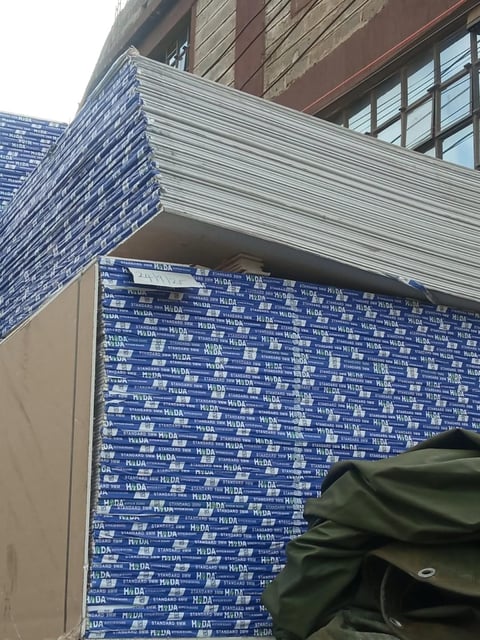 Modern building exterior with corrugated metal overhang and blue patterned wall panel featuring repeated text