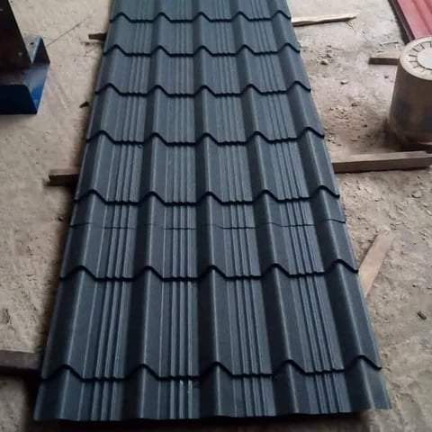 Dark gray corrugated metal roofing sheet with interlocking tile pattern laid on ground