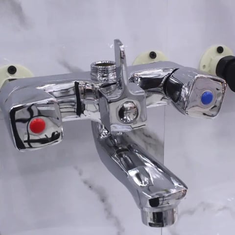Overhead view of a chrome polished kitchen or bathroom faucet with red and blue decorative valve handles on white marble surface