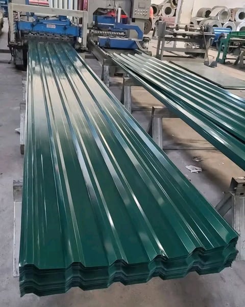 Green corrugated metal roofing panels lined up in a manufacturing facility