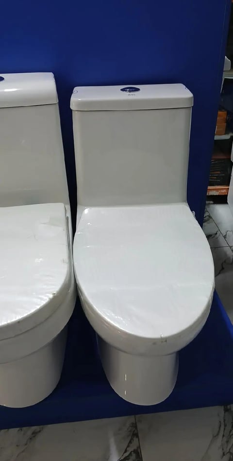 Two white ceramic toilets displayed side by side on a blue background in a showroom setting