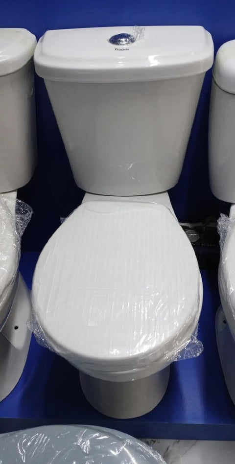 White ceramic toilet with closed seat and tank displayed in a showroom with blue background