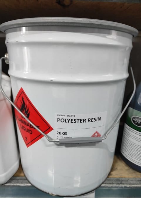 Large white bucket labeled polyester resin, 20kg, with red hazard warning label and metal handle
