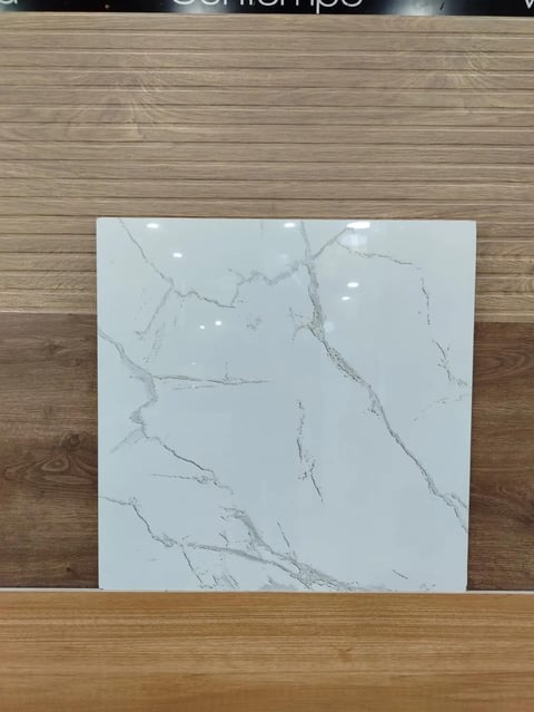 White marble tile sample with gray veining displayed on wooden floor and wall