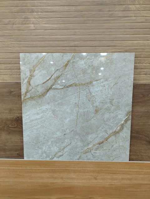 Light gray marble tile with gold veining displayed against wooden flooring