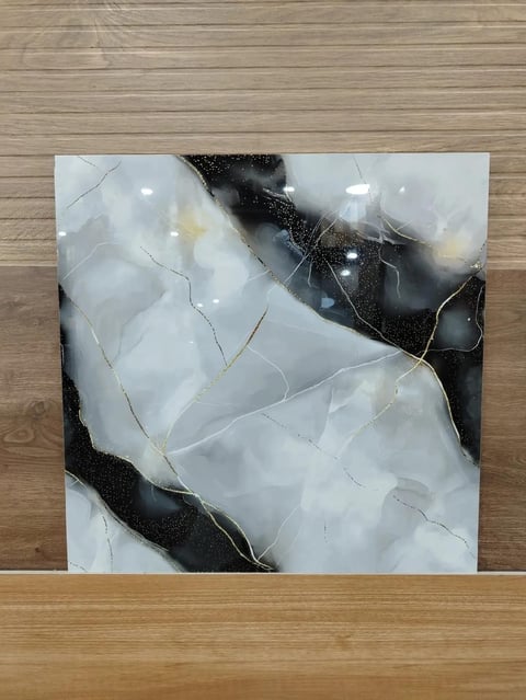 Abstract marble tile with white and black swirled patterns, displayed on a wooden surface