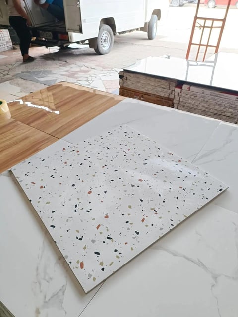 Terrazzo tile sample with colorful aggregate flecks displayed on white countertop in showroom setting