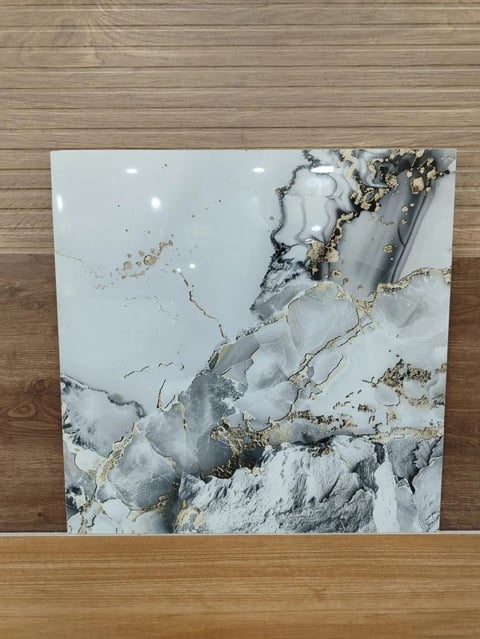 White and gray marble tile with gold and black veining, leaning against wooden floor