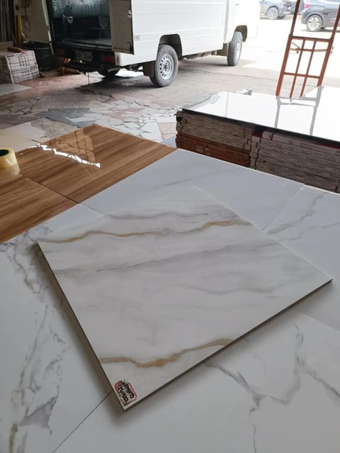 Marble tile samples displayed on showroom floor with trailer and wood flooring samples visible in background