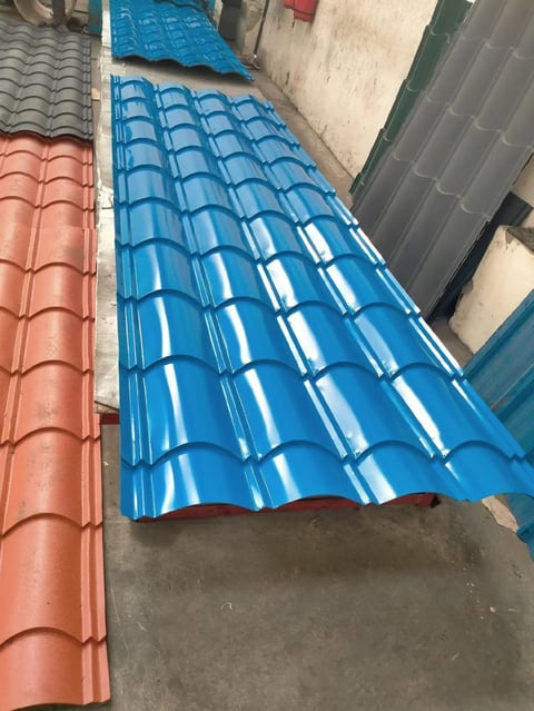 Blue corrugated metal roofing sheets laid on ground next to red and gray roof tiles at construction site