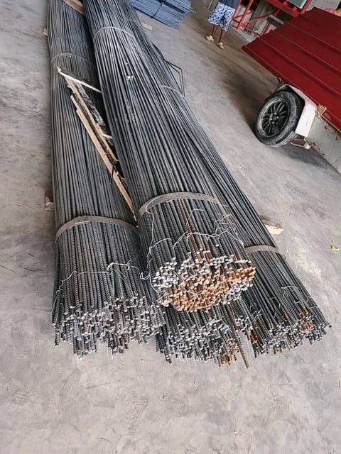 Bundled steel reinforcing bars stacked on concrete ground at construction site